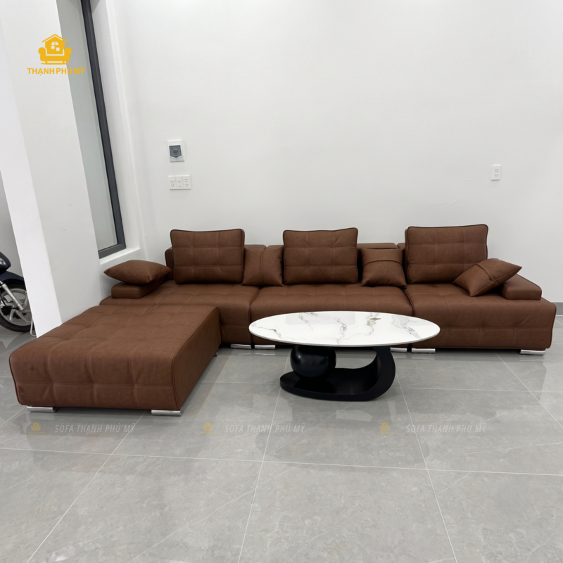 Băng ghế sofa dài 3m5 bọc da nâu bò đặt vào tỷ lệ thực tế không gian phòng khách tại Buôn Hồ, đi kèm bàn trà mặt đá.