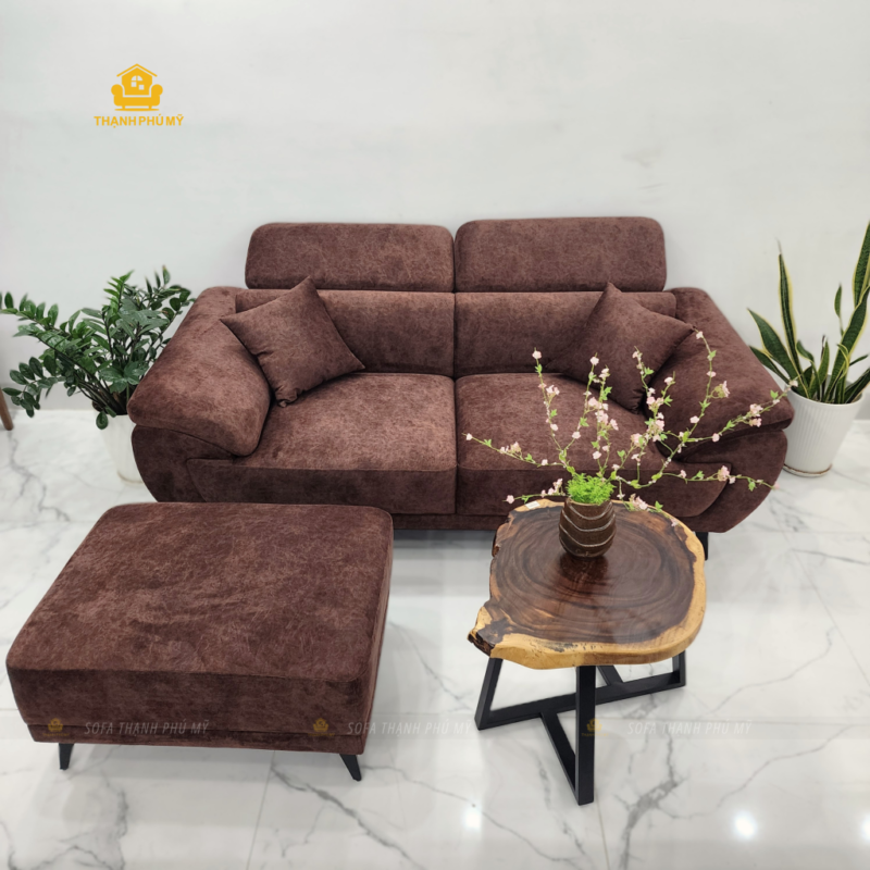 Bộ sofa được đóng mới với kích thước 2m x 95cm, đi kèm đôn nối rời 60x80cm. Toàn bộ ghế sử dụng vải nhung marble màu nâu camel sẫm, kết hợp tựa đầu nâng hạ cơ học, hai gối ôm cùng tông và chân kim loại sơn đen dáng thon giúp robot lau nhà dễ dàng di chuyển bên dưới. Giá hoàn thiện của bộ sofa là 12,5 triệu đồng (giá niêm yết 13,9 triệu đồng).