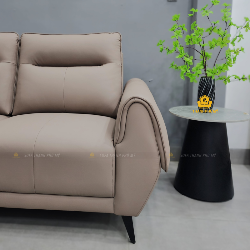 Cận cảnh tay vịn bo tròn và đường viền chỉ trên sofa văng da simili màu be thiên hồng.