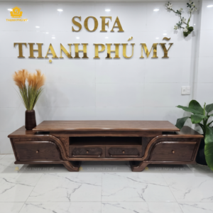 Mặt trước tổng thể của thành phẩm kệ tivi gỗ Óc Chó 2 tầng thiết kế giật cấp, màu nâu socola trầm, được trưng bày dưới bảng hiệu showroom Nội Thất Thạnh Phú Mỹ tại Buôn Ma Thuột.