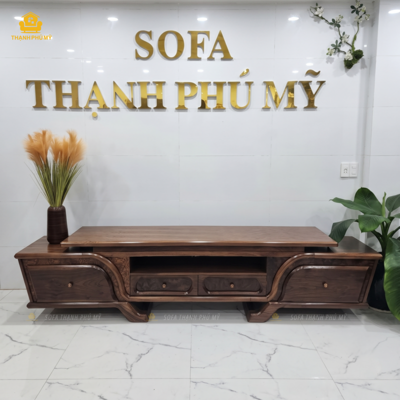 Mặt trước tổng thể của thành phẩm kệ tivi gỗ Óc Chó 2 tầng thiết kế giật cấp, màu nâu socola trầm, được trưng bày dưới bảng hiệu showroom Nội Thất Thạnh Phú Mỹ tại Buôn Ma Thuột.